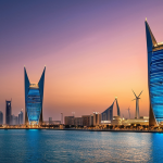 **Bahrain World Trade Center:** "A panoramic view of the Bahrain World Trade Center at sunset. The two towers are connected by wind turbines, illuminated against the twilight sky. Below, a bustling cityscape of Manama spreads out with the Persian Gulf shimmering in the background. Style: realistic, vibrant colors."